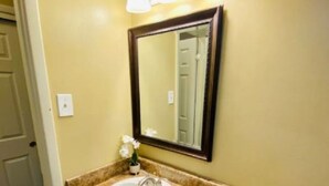 A bathroom with a sink, mirror, and three wall-mounted lights. - Near Downtown Stunning Course-View Flat (Birmingham)