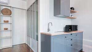 A modern kitchen with a built-in sink, a coffee machine, and a microwave. There is a wooden countertop and a blue cabinet with drawers. - GuestReady - Bourse Maison (Porto)