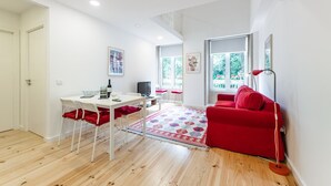 Una sala de estar moderna con un sofá rojo, una mesa de comedor con sillas y un televisor.