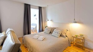 A bedroom with a bed, a chair, a bedside table, and a lamp.