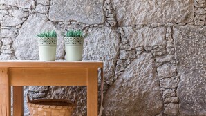A wooden table with two potted plants and a woven basket against a stone wall. - GuestReady - Chapel`s Garden (Caminha)