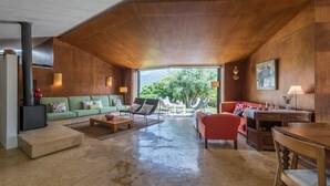 A spacious living room with a high ceiling, a fireplace, a sofa, a red couch, and a dining area with a table and chairs. - GuestReady - Chapel`s Garden (Caminha)