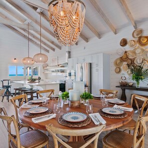 A spacious dining area with a round wooden table set for six, surrounded by wooden chairs. - The Sandbar Luxury Oceanfront Home, 5 Bedroom 5 Bath, Infinity Pool/Hot Tub (Exuma)