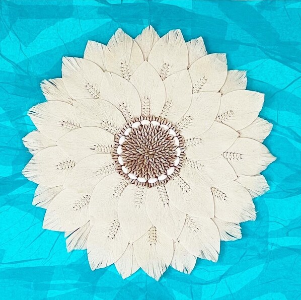 A circular wooden artwork with a central pattern and radiating segments, set against a textured blue background. - The Sandbar Luxury Oceanfront Home, 5 Bedroom 5 Bath, Infinity Pool/Hot Tub (Exuma)