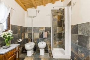 A bathroom with a shower, toilet, bidet, and marble-tiled walls. - Authentic Sicilian Charm With Pool, Sea View, Parking & Wifi (Avola)
