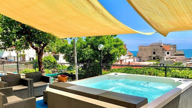 A hot tub with wicker furniture and a view of the sea. - Eden Holiday Apartment (Minori)