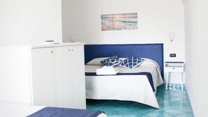 A hotel room with a bed, a small table, and a wall-mounted TV. - Eden Holiday Apartment (Minori)