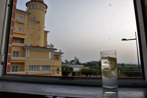 Un vaso de agua con una rodaja de limón sobre un alféizar.