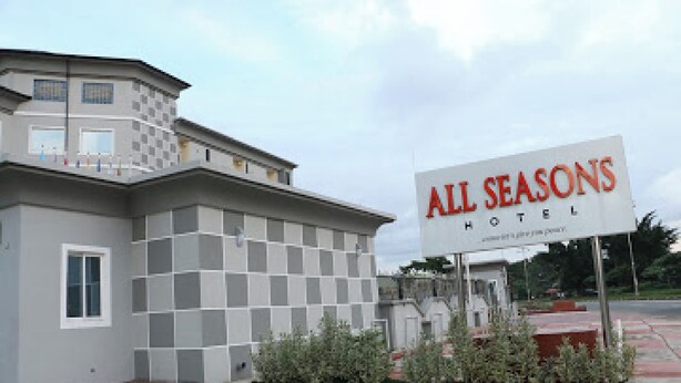 Et hotel med et skilt, der viser 'ALL SEASONS HOTEL', og et moderne arkitektonisk design.