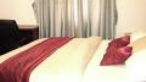 A hotel room with two beds, a desk, and a window with curtains. - Room-adanma Hotel and Suites - Guest Roo (Abuja)
