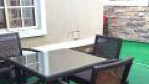 A dining area with a table and chairs, a stone wall, and a window with multiple panes. - Room-adanma Hotel and Suites - Guest Roo (Abuja)