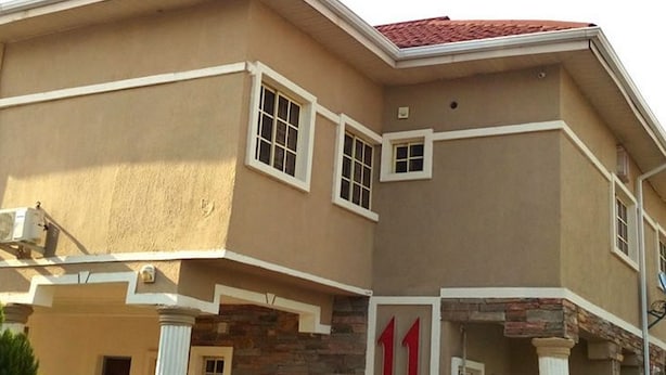A multi-story house with a stone facade, multiple windows, and a red roof. - Room-adanma Hotel and Suites - Guest Roo (Abuja)