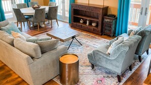 Una sala de estar con sofá, sillones, una mesa de centro, televisor y un comedor con sillas y mesa.