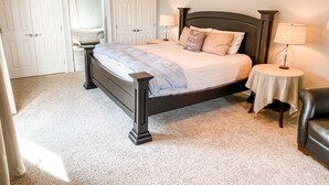 Un dormitorio con cama, dos mesitas de noche, una silla y un armario.