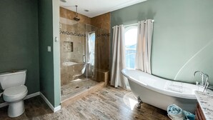 Un baño moderno con ducha envuelta en vidrio, una bañera independiente y un inodoro.