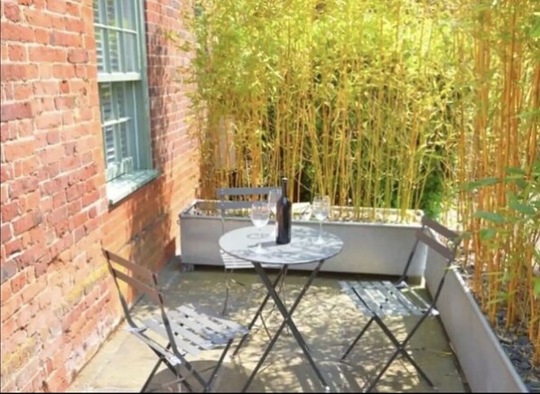 Enjoy casual dining or socializing in this outdoor space with a round table and two chairs.