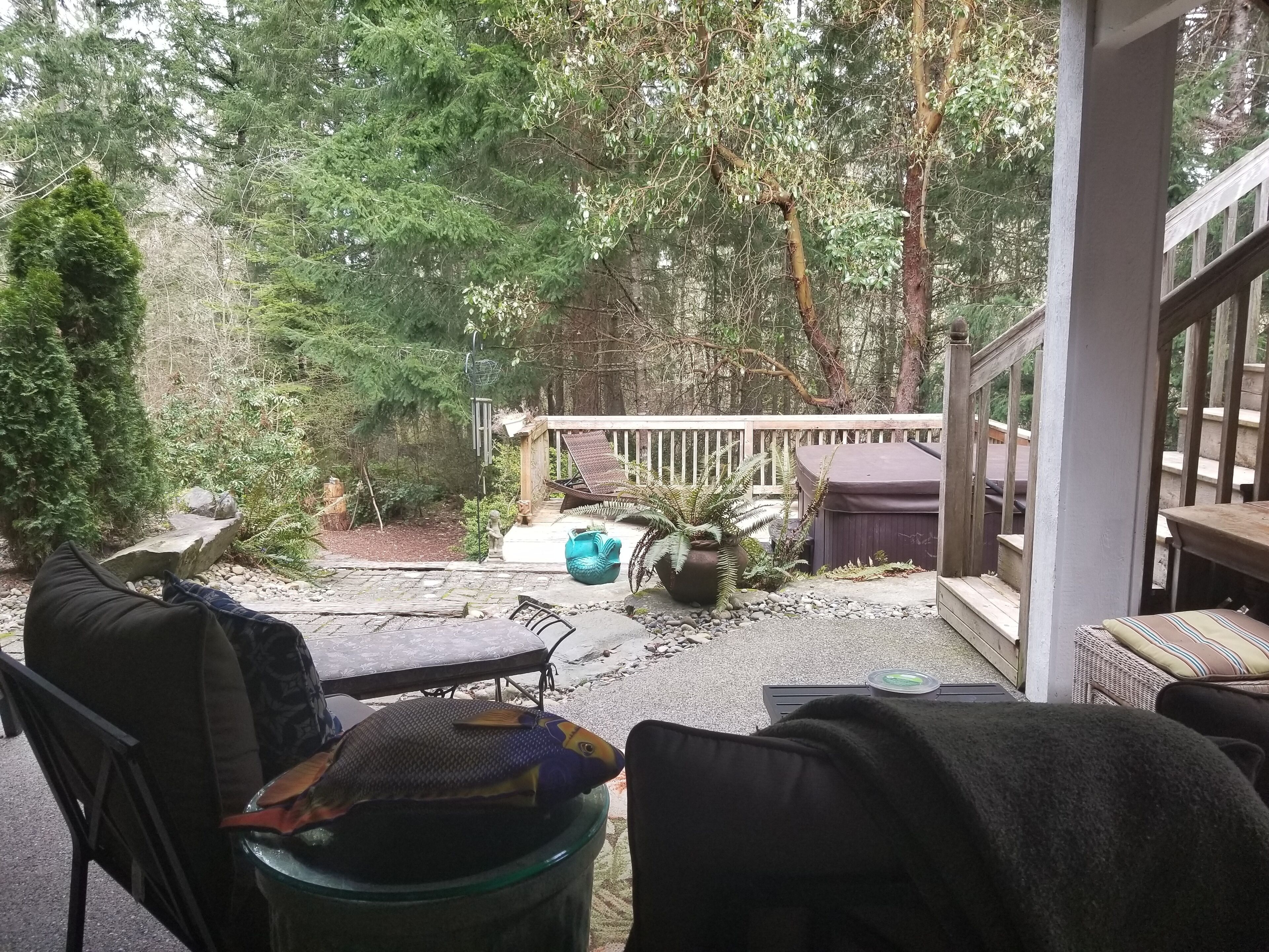 A covered patio with outdoor furniture, a hot tub, and a wooden deck.