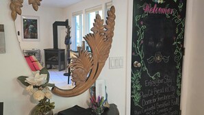 Una habitación con un espejo grande, una pizarra con la palabra 'Welcome' y 'Enjoy Your Stay' escritas, y un adorno de madera sobre una consola.