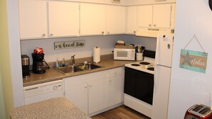 Una cocina pequeña con armarios blancos, un microondas, una estufa y un tostador.