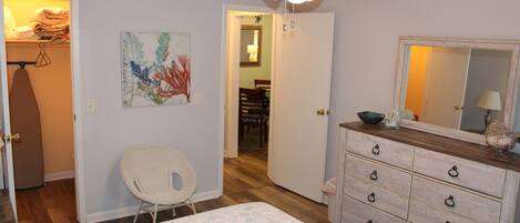 A bedroom with a bed, a dresser, a chair, and a ceiling fan.