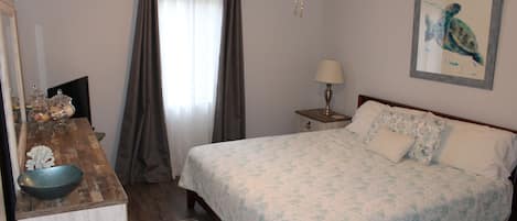 A bedroom with a bed, a desk, a lamp, and a ceiling fan.