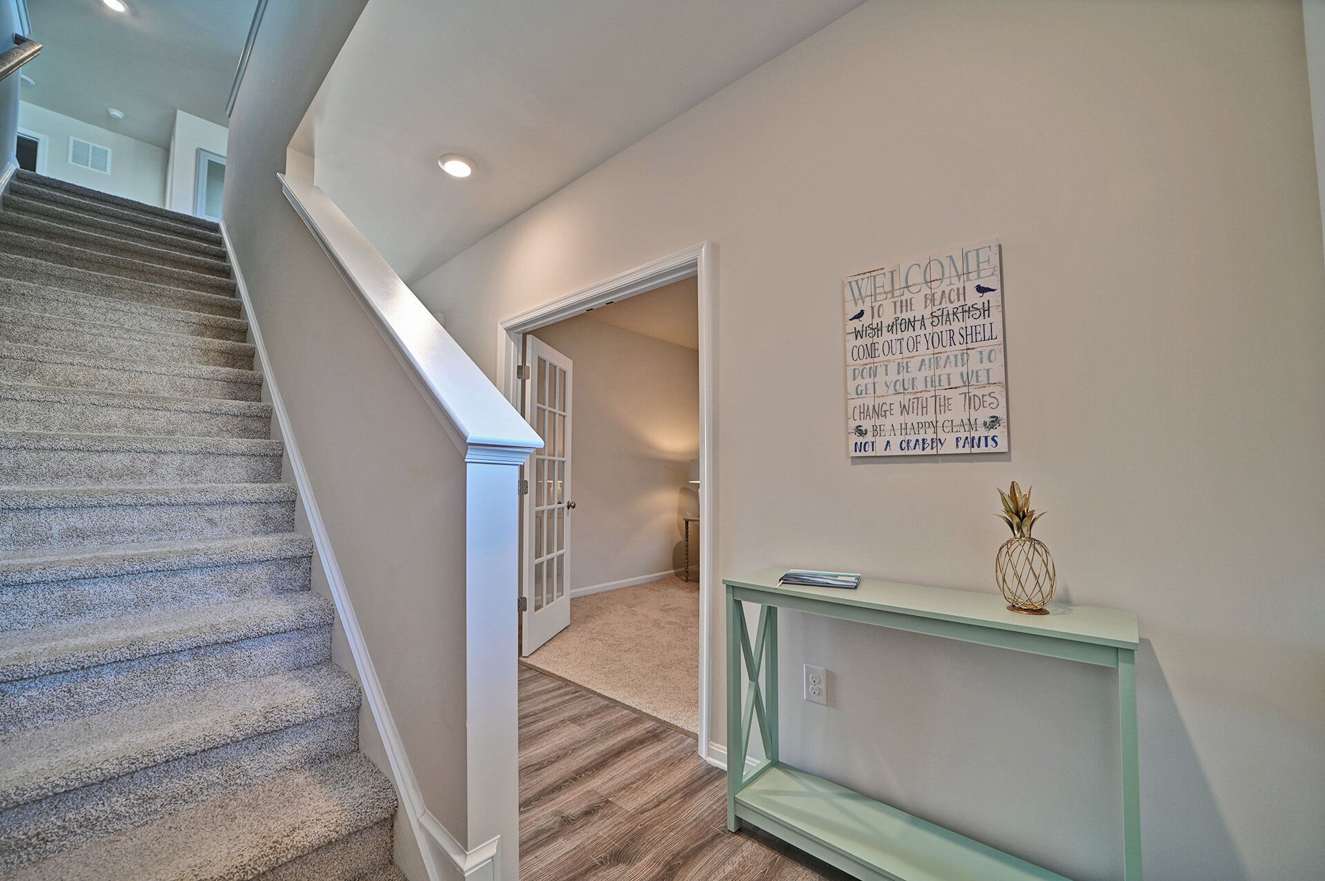 Una escalera conduce a una habitación con un letrero en la pared y una consola decorada con un objeto ornamental.