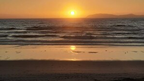 A beach at sunset with the sun low on the horizon, reflecting on the water. - Ocean view beautiful apartament with pool and jacuzzi, furnished. (Tijuana y Rosarito)