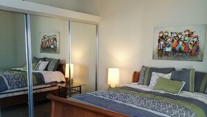 A bedroom with a large bed, a mirror, two bedside tables with lamps, and a colorful painting on the wall. - Ocean view beautiful apartament with pool and jacuzzi, furnished. (Tijuana y Rosarito)