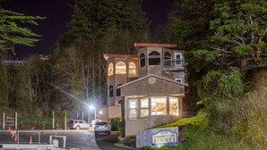 Uma pousada de dois andares com varanda, uma placa indicando ser o Smuggler's Cove Resort e vista da floresta ao redor.
