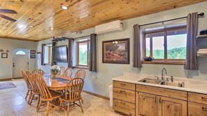 A wooden interior with a dining area, kitchen, and large windows. - Western Blue Skies in Country (Hot Springs)