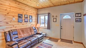 A wooden-paneled room with a leather sofa, a lamp, and a door. - Western Blue Skies in Country (Hot Springs)