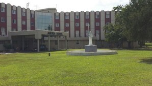 A hotel with a central entrance, a statue, and a well-maintained lawn. - Room-agura Hotel - Guest Room (Abuja)