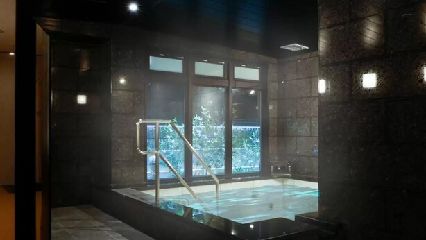 Un área de spa con un jacuzzi, una puerta de cristal que da al exterior y una escalera metálica.