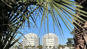 Ein Hotel am Wasserufer, dessen Spiegelung sich im Wasser zeigt, umgeben von Palmen.