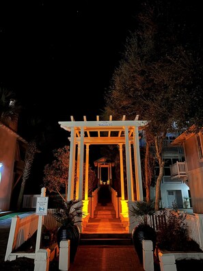 Un chemin piétonnier nocturne menant à une zone abritée, où un panneau indique « Passage piéton n° 8 ».