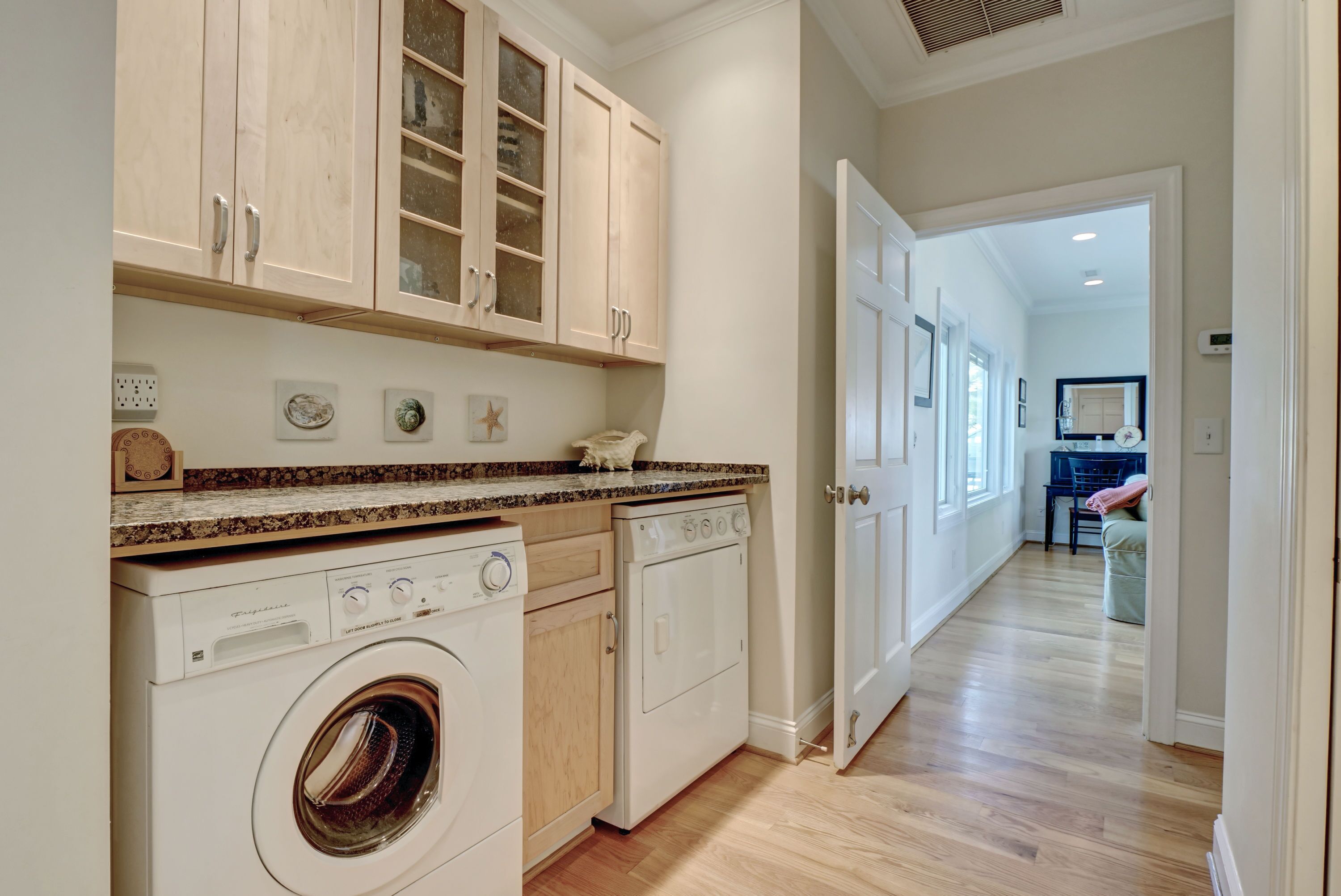 A laundry room with a washing machine, dryer, and cabinets.