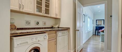A laundry room with a washing machine, dryer, and cabinets.
