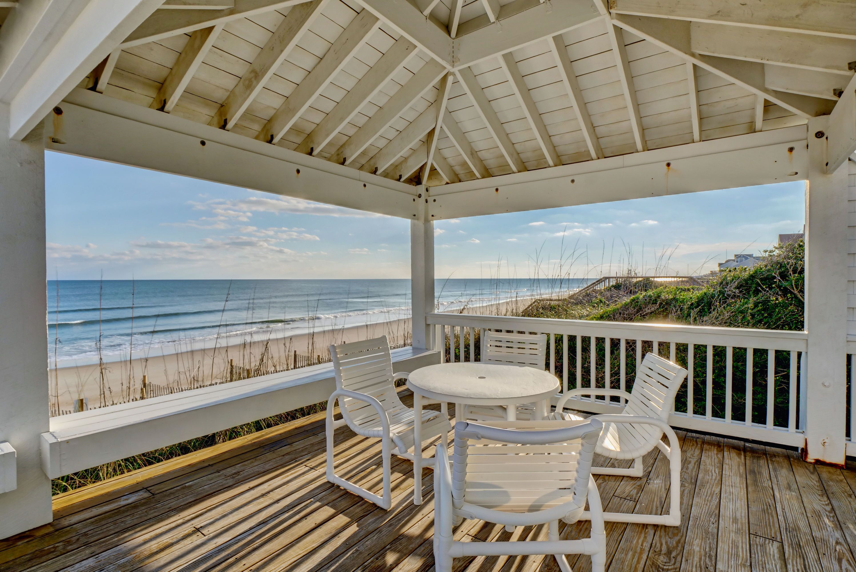 A covered outdoor seating area with a view of the beach and ocean.