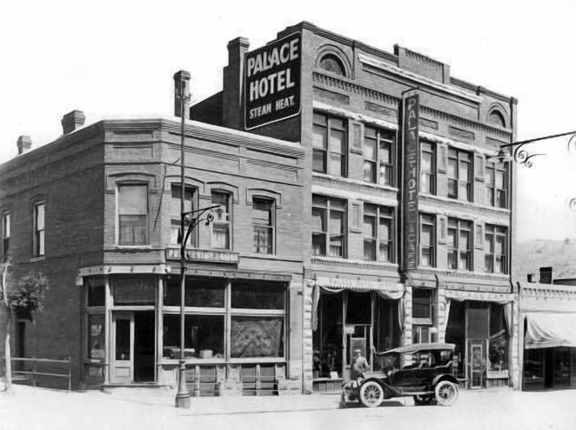 Een historisch gebouw met een bord waarop staat: “Palace Hotel Steam Heat”. Het heeft een klassieke architectuur, meerdere verdiepingen, grote ramen en een opvallende hoingang.