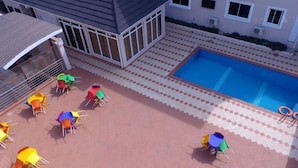 Uma área de piscina com cadeiras coloridas e uma piscina azul cristalina.