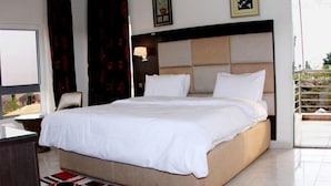 Quarto de hotel com uma cama grande, uma mesa, uma cadeira, uma janela e uma varanda.