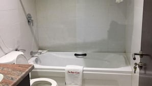 Casa de banho com banheira, sanita e toalheiro com toalha.