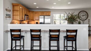 A kitchen with wooden cabinets, a stainless steel refrigerator, and a large island with bar stools. - The View on Bull Shoals Lake! (Lakeview)