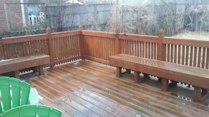 Een houten terras met banken en een groene stoel.