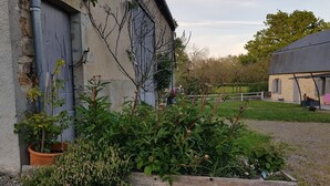 A rustic building with a stone exterior, a wooden deck, and a garden area with various plants and flowers. - Renovated 18th century mill "Domaine vous uniquement vous, with private swimming pool". (Montapas)