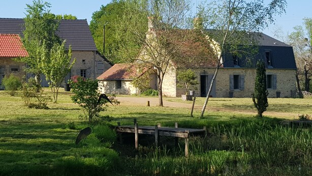 A rustic stone building with a red-tiled roof, surrounded by a grassy field and trees. - Renovated 18th century mill "Domaine vous uniquement vous, with private swimming pool". (Montapas)