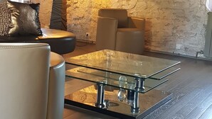 A modern living room with a glass coffee table, leather sofa, and a stone wall. - Renovated 18th century mill "Domaine vous uniquement vous, with private swimming pool". (Montapas)