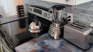 Eine Küche mit einem Edelstahlherd, einem Mixer, einem Toaster und einer Mikrowelle.