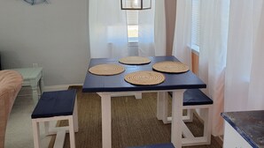 Ein Essbereich mit einem Tisch, gedeckt für vier Personen, mit gewebten Platzsets und einer hängenden Leuchte.