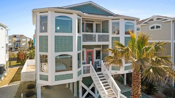 A multi-story building with a balcony, a staircase, and a palm tree.